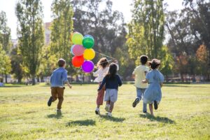 Crianças brincando com balões no parque dos dinossauros para crianças