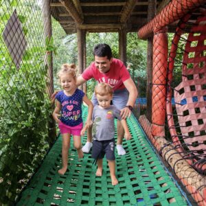 Pai brincando com os filhos no brinquedão da Vila Encantada