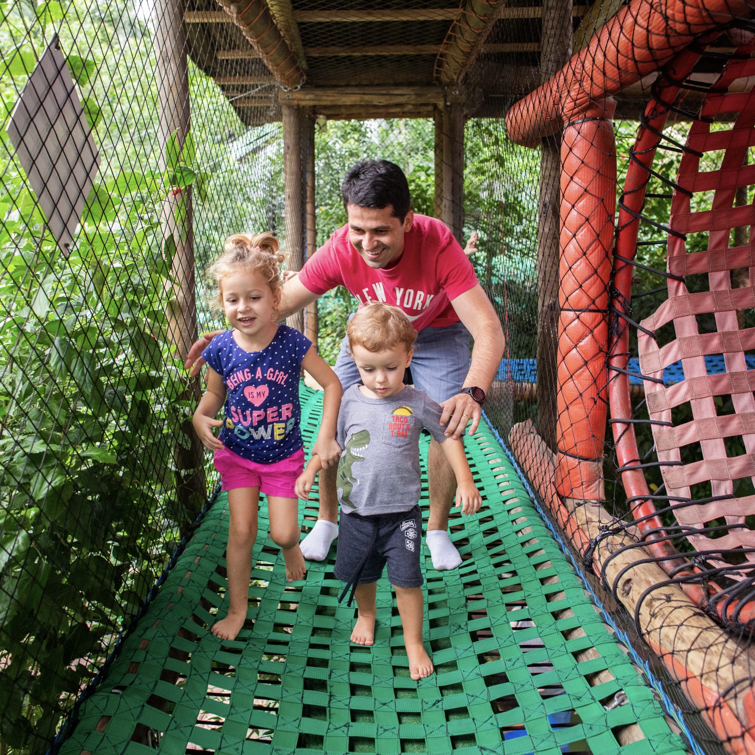 Pai brincando com os filhos no brinquedão da Vila Encantada